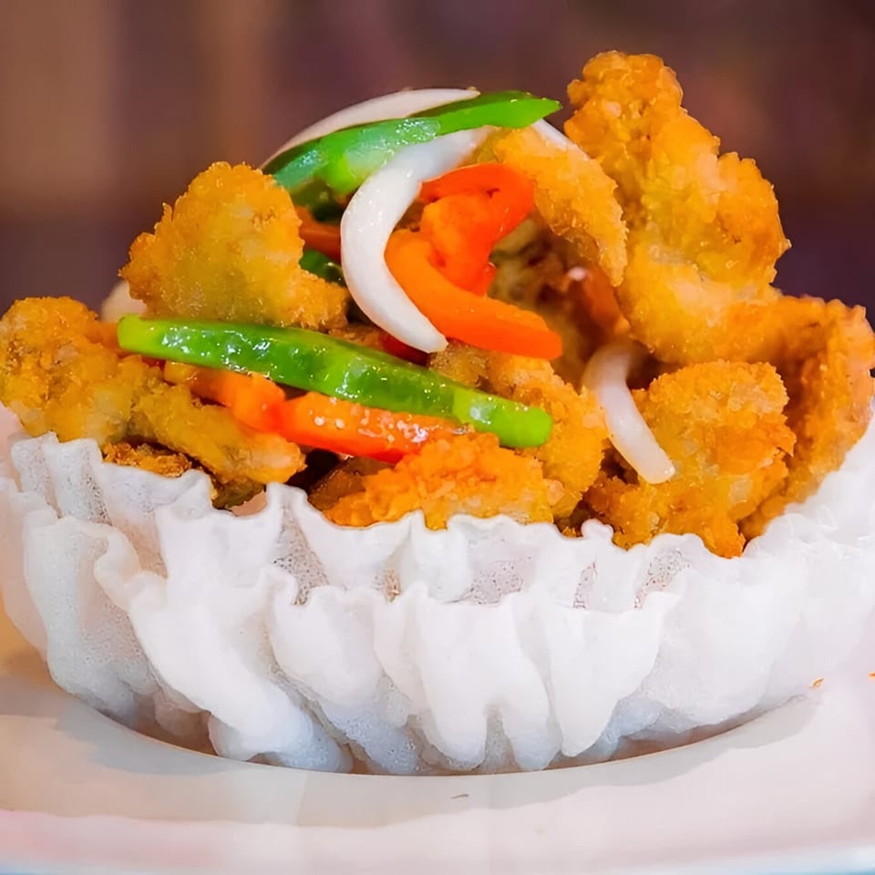 Golden Bamboo's crispy fried vegetarian dish with bell peppers and onions in a white edible bowl.