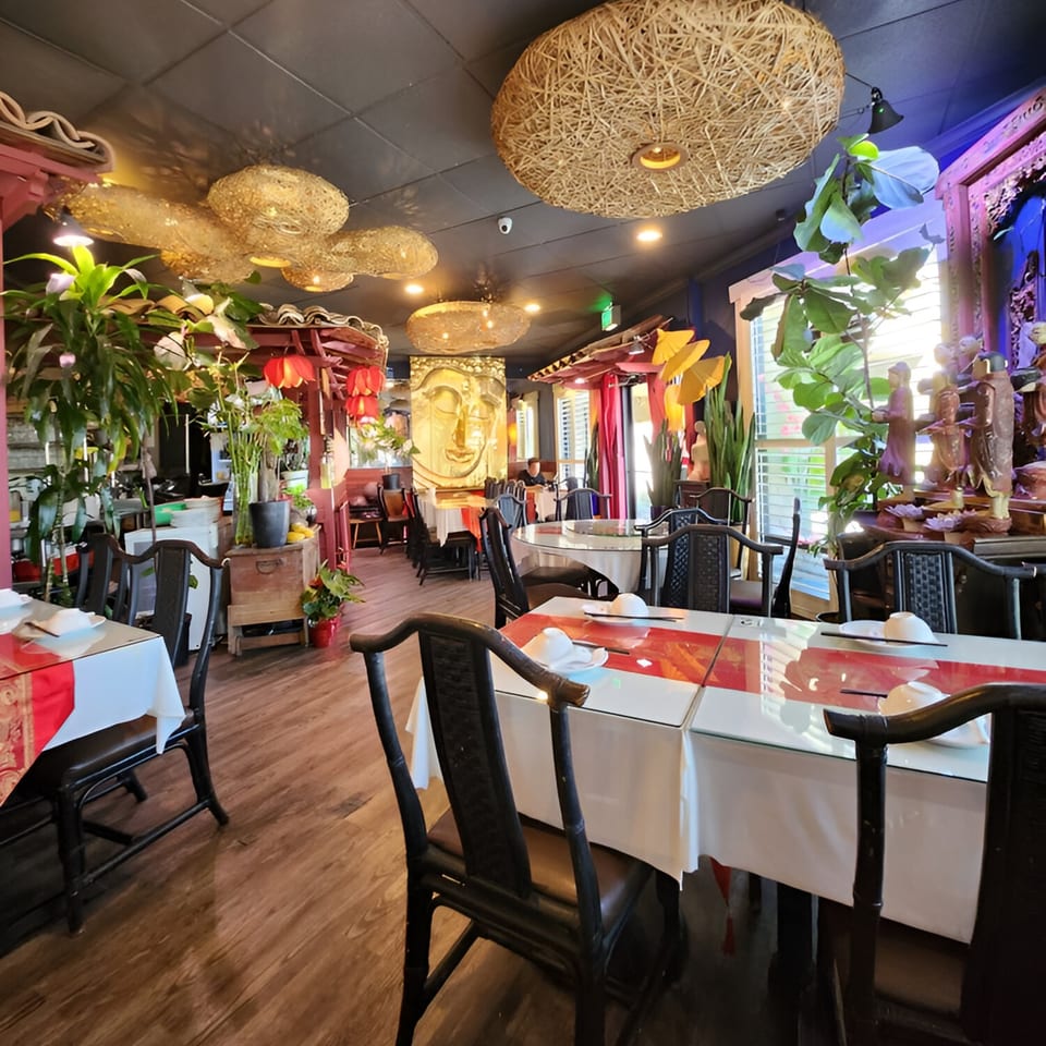 Interior of Golden Bamboo Vegetarian Restaurant with ornate decor, Buddha head, and set tables.